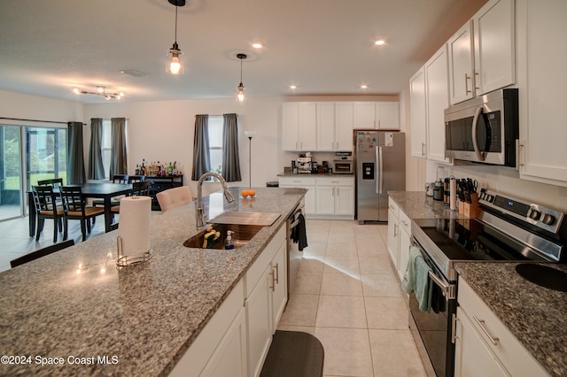 kitchen featuring sink, white cabinetry, decorative light fixtures, appliances with stainless steel finishes, and dark stone counters