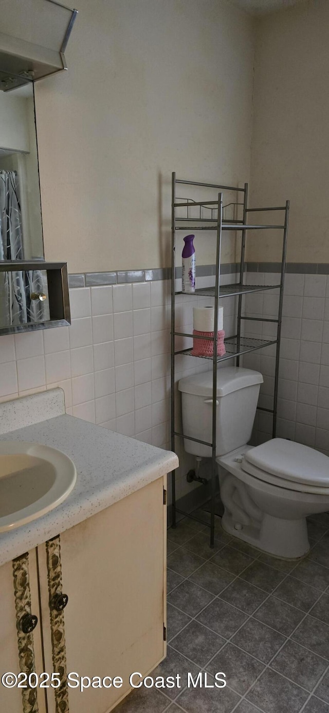 bathroom with tile walls, tile patterned floors, vanity, and toilet