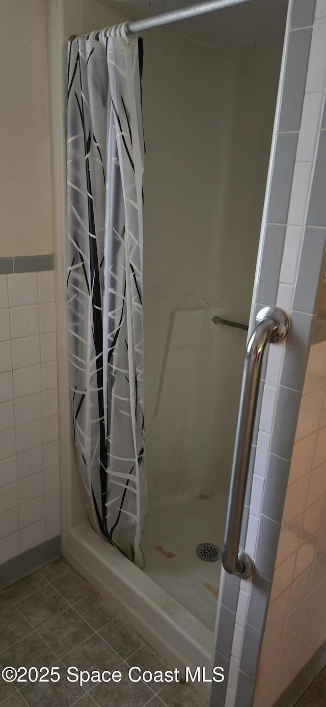 bathroom with curtained shower, tile walls, and tile patterned flooring