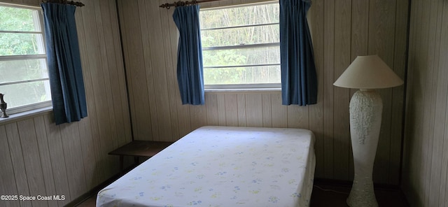 bedroom with wooden walls and multiple windows