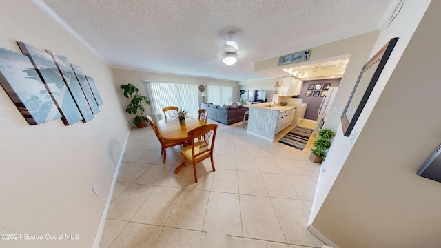 tiled dining space featuring a textured ceiling, ceiling fan, and crown molding