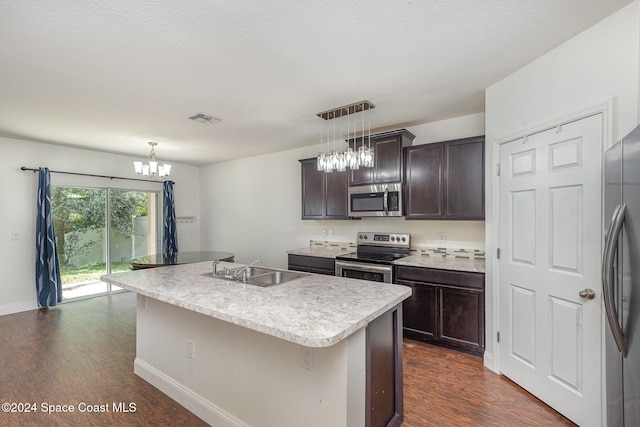 kitchen with stainless steel appliances, dark hardwood / wood-style flooring, sink, a kitchen island with sink, and decorative light fixtures