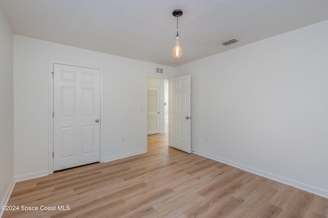 unfurnished bedroom featuring a textured ceiling, a closet, and light wood-type flooring