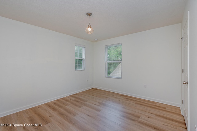 empty room with light hardwood / wood-style floors and a textured ceiling