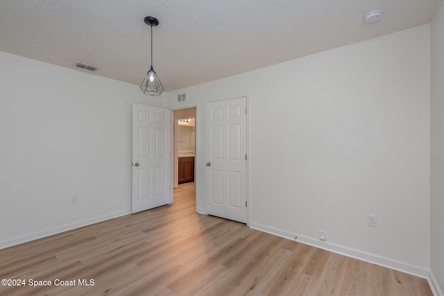 spare room featuring light hardwood / wood-style flooring and a textured ceiling