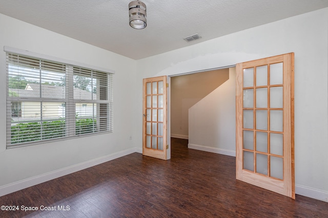 unfurnished room with french doors, dark wood-type flooring, and a textured ceiling