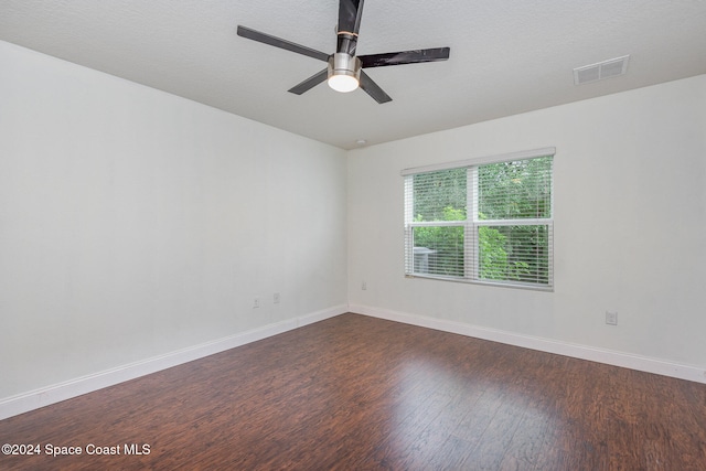 spare room featuring dark wood-type flooring, ceiling fan, and a textured ceiling