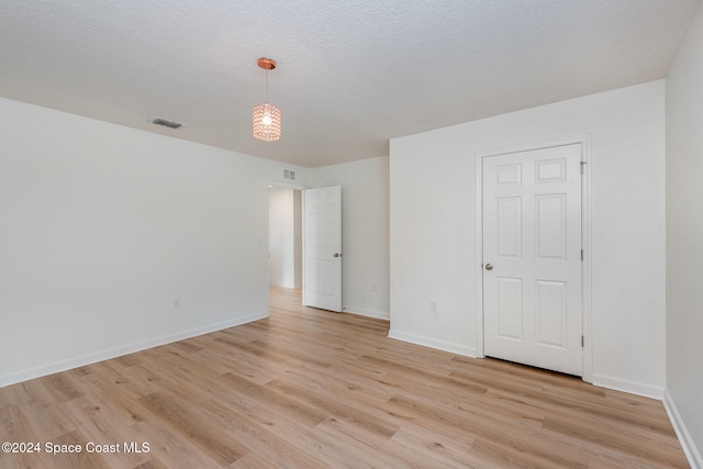 spare room with light wood-type flooring and a textured ceiling