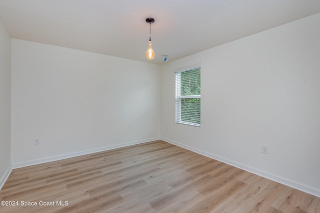 spare room featuring light hardwood / wood-style floors and a textured ceiling