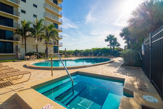 community pool with a patio and a hot tub