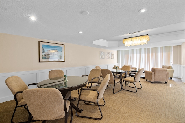 dining room with a wainscoted wall, a textured ceiling, and a decorative wall