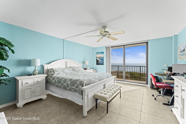 bedroom featuring expansive windows, light tile patterned floors, a ceiling fan, a textured ceiling, and access to outside