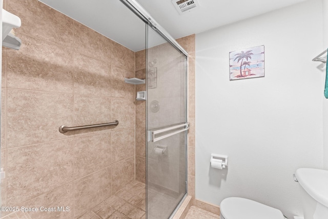 bathroom featuring a shower stall, toilet, baseboards, and visible vents