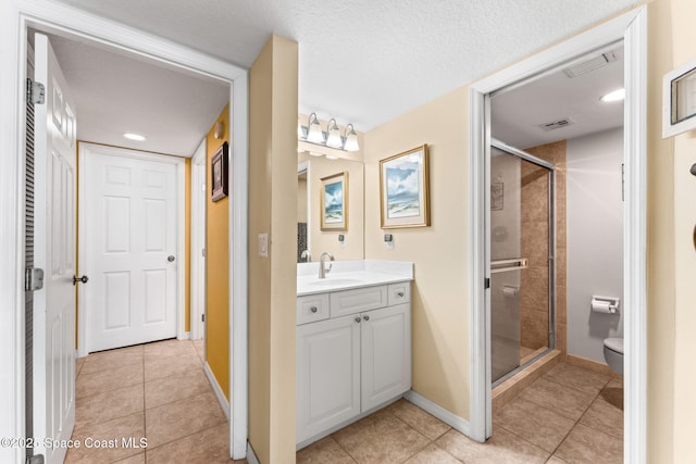 bathroom featuring visible vents, toilet, a stall shower, tile patterned floors, and vanity