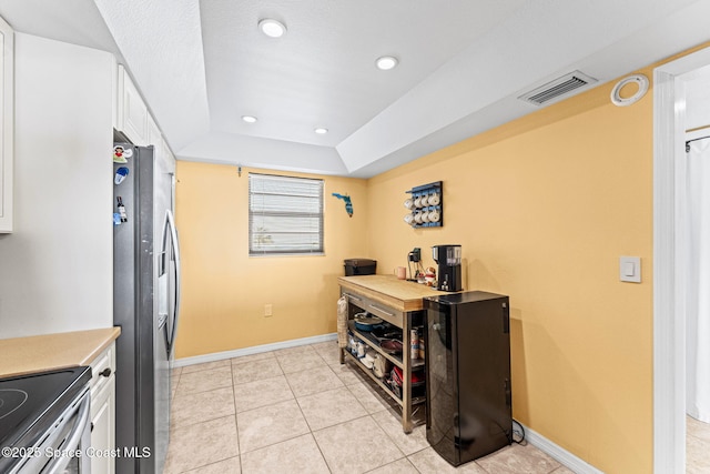 kitchen featuring visible vents, baseboards, a tray ceiling, stainless steel fridge with ice dispenser, and white cabinets