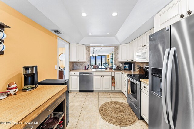 kitchen with visible vents, backsplash, appliances with stainless steel finishes, light tile patterned floors, and a raised ceiling