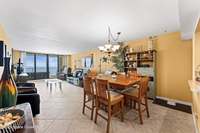 dining space featuring light tile patterned floors, expansive windows, a notable chandelier, and a textured ceiling