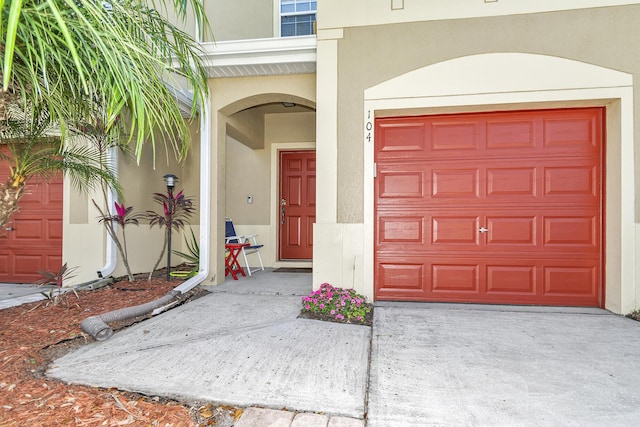 2650 Revolution St Unit 104, Melbourne, FL 32935 - doorway to property with stucco siding, a garage, and concrete driveway