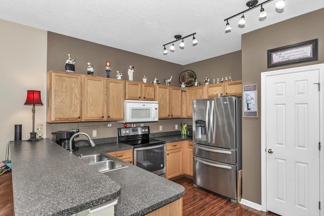 2650 Revolution St Unit 104, Melbourne, FL 32935 - kitchen with stainless steel appliances, a sink, a peninsula, dark countertops, and dark wood-style floors