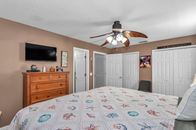 bedroom with multiple closets, a textured ceiling, and ceiling fan