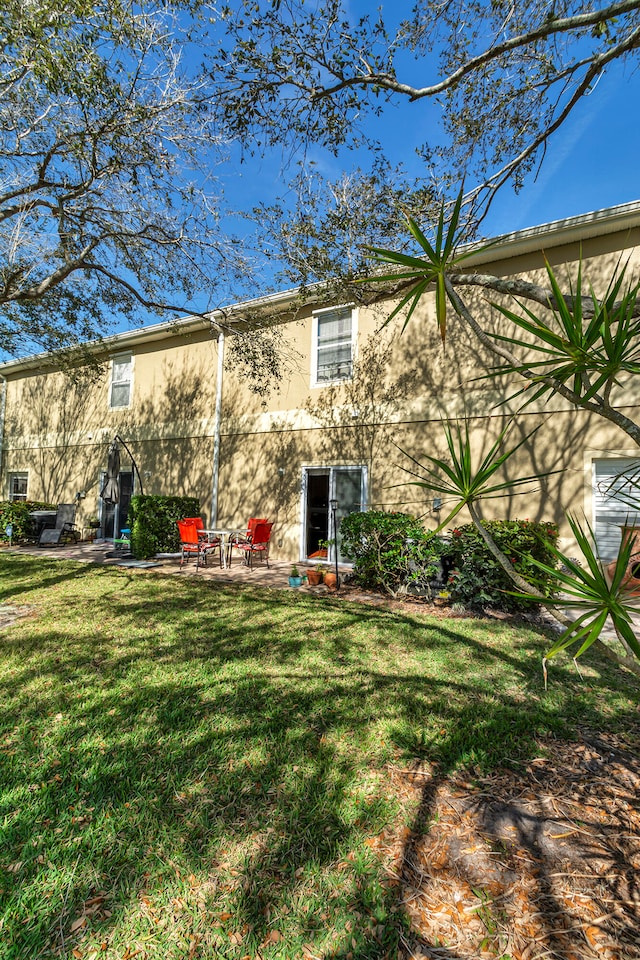 back of property featuring a lawn and a patio