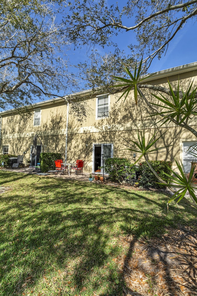 2650 Revolution St Unit 104, Melbourne, FL 32935 - back of house featuring a lawn, stucco siding, and a patio area