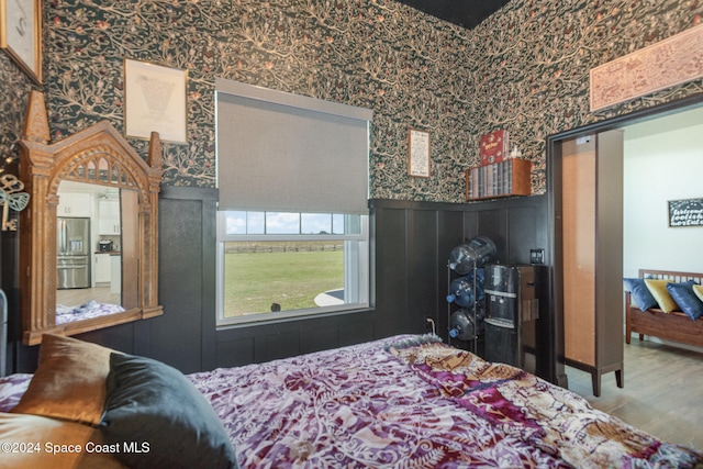 bedroom featuring hardwood / wood-style floors and stainless steel fridge