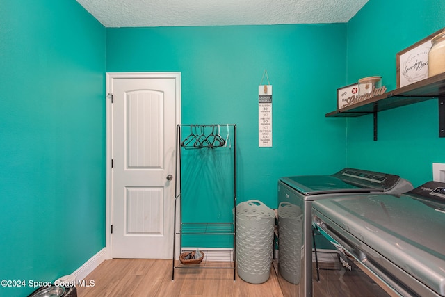 laundry area featuring a textured ceiling, separate washer and dryer, and light hardwood / wood-style flooring