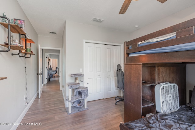 bedroom featuring wood-type flooring, a textured ceiling, a closet, and ceiling fan