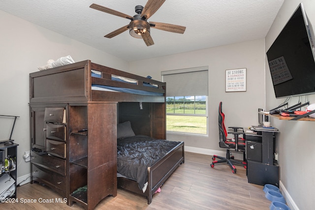 bedroom with ceiling fan, light wood-type flooring, and a textured ceiling