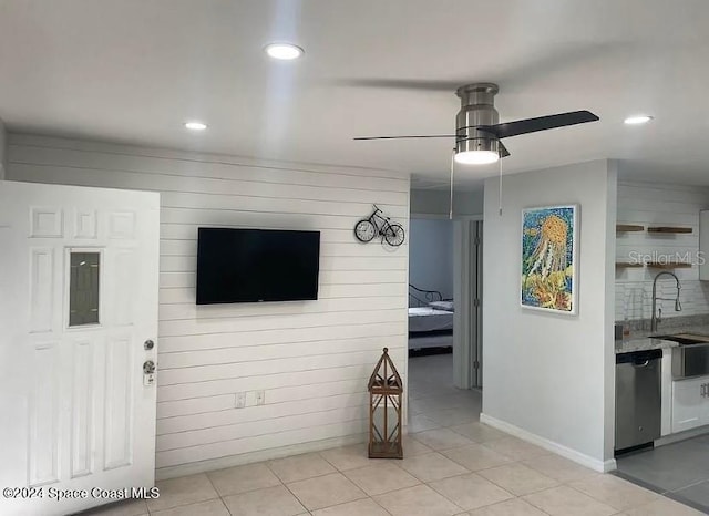 tiled living room featuring wood walls, sink, and ceiling fan