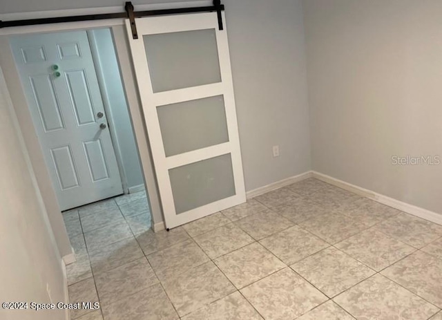 unfurnished room featuring a barn door and light tile patterned flooring