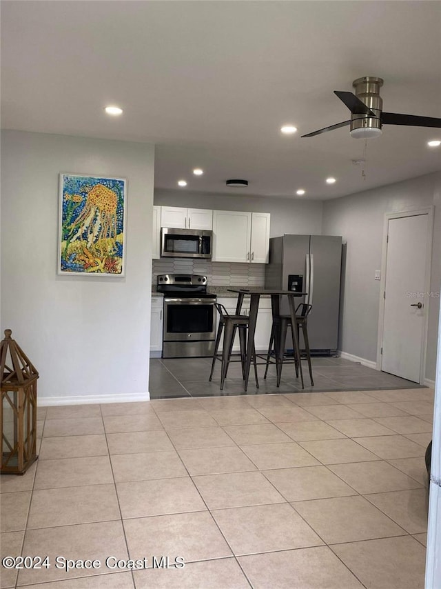 kitchen featuring stainless steel appliances, white cabinetry, light tile patterned floors, and tasteful backsplash