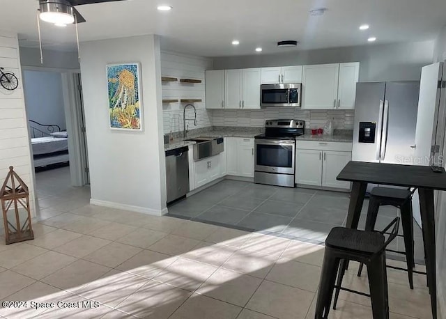 kitchen with white cabinets, sink, light tile patterned flooring, backsplash, and appliances with stainless steel finishes