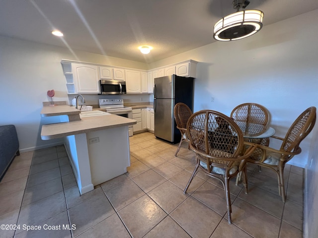 kitchen with white cabinets, kitchen peninsula, stainless steel appliances, and sink