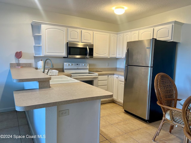 kitchen featuring kitchen peninsula, white cabinetry, sink, and appliances with stainless steel finishes