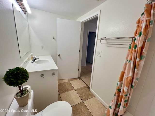 bathroom with toilet, vanity, and tile patterned floors