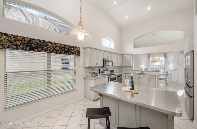 kitchen with hanging light fixtures, appliances with stainless steel finishes, a center island, and plenty of natural light