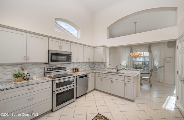 kitchen featuring light stone counters, plenty of natural light, high vaulted ceiling, and stainless steel appliances