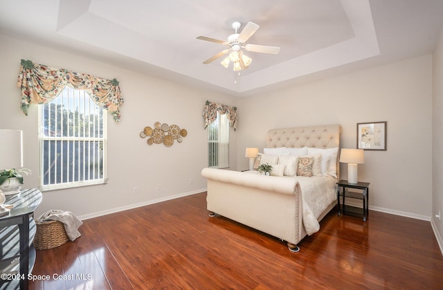 bedroom featuring dark hardwood / wood-style floors, ceiling fan, and a tray ceiling