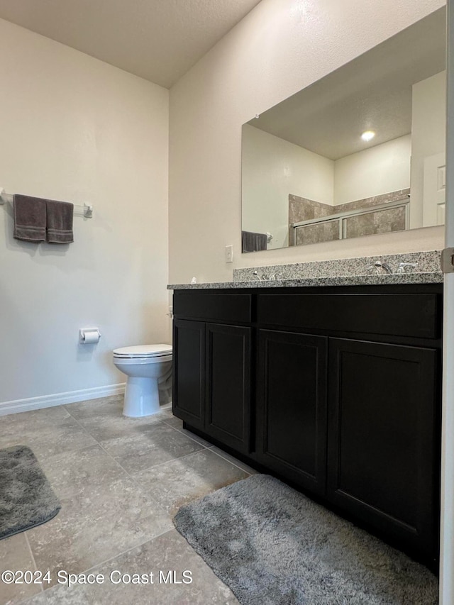 bathroom with vanity, toilet, and a shower with door