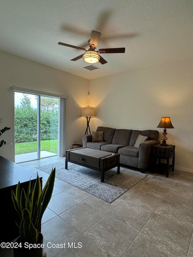 living room with ceiling fan, a textured ceiling, and light tile patterned floors