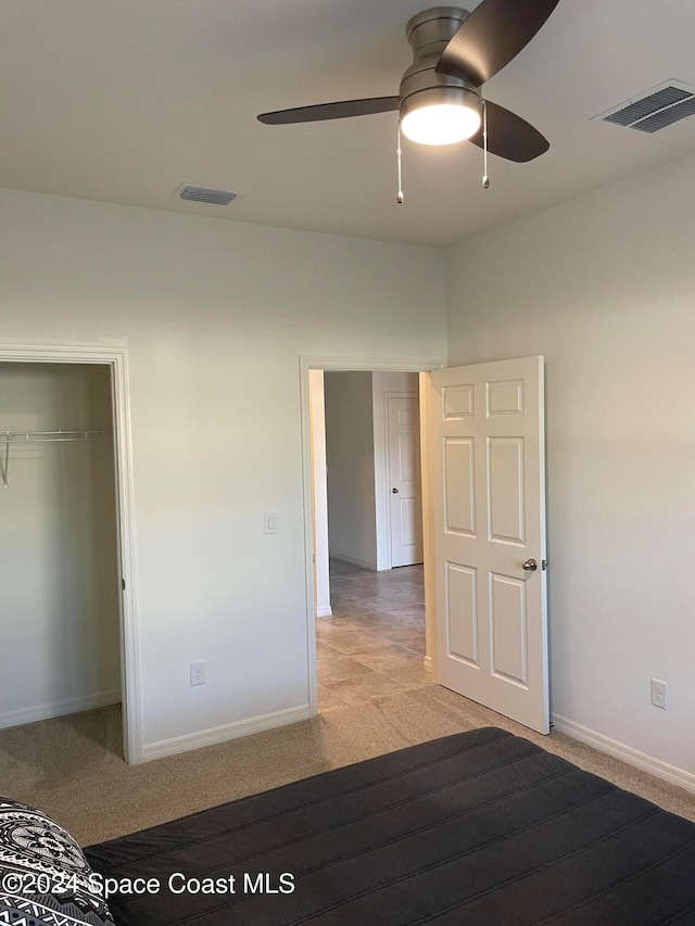 unfurnished bedroom with light carpet, ceiling fan, and a closet