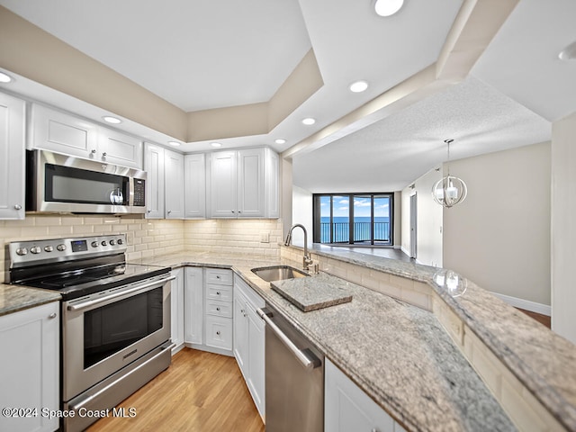 kitchen with stainless steel appliances, light stone counters, white cabinets, sink, and light wood-type flooring