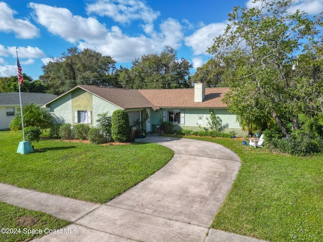 single story home with a front yard, concrete driveway, a chimney, and stucco siding