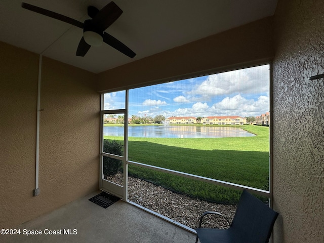 unfurnished sunroom with ceiling fan and a water view