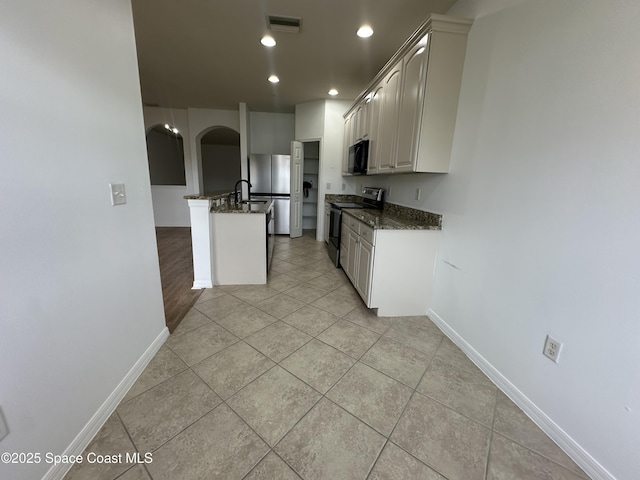 kitchen with white cabinets, appliances with stainless steel finishes, kitchen peninsula, and light tile patterned flooring