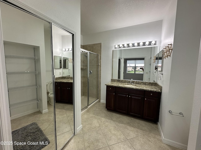 bathroom with a textured ceiling, vanity, an enclosed shower, and toilet