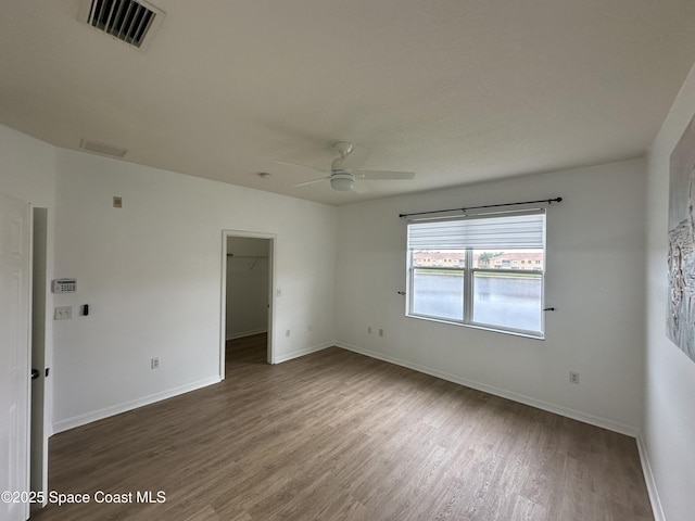 empty room with ceiling fan and dark hardwood / wood-style flooring