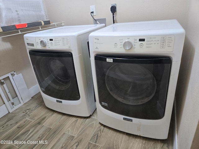 clothes washing area with separate washer and dryer and light wood-type flooring